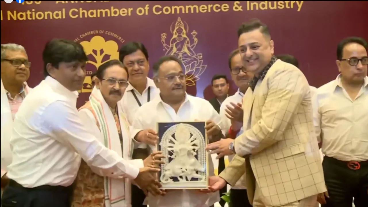 Group of men in formal attire presenting a framed sculpture of a Hindu deity during a ceremony, backdrop reads National Chamber of Commerce & Industry