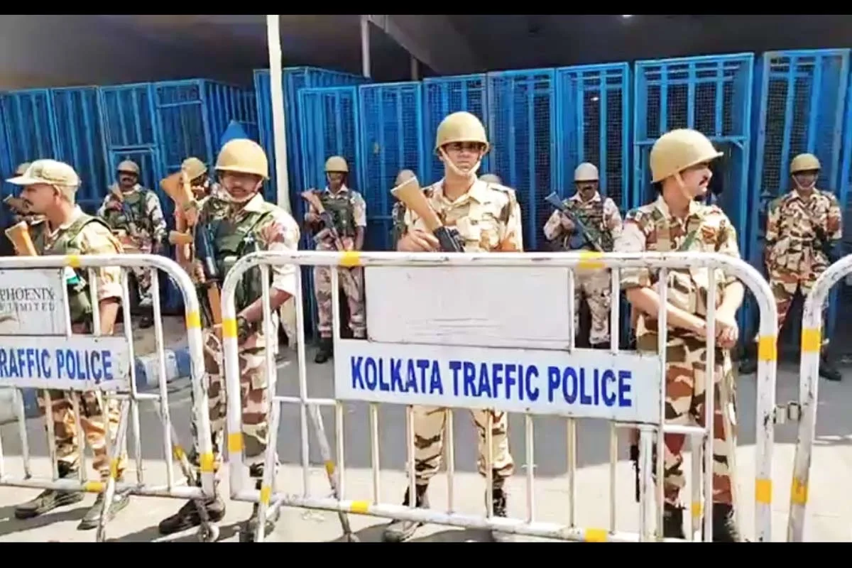 Group of uniformed officers behind metal barriers, with a prominent 'Kolkata Traffic Police' sign in front.