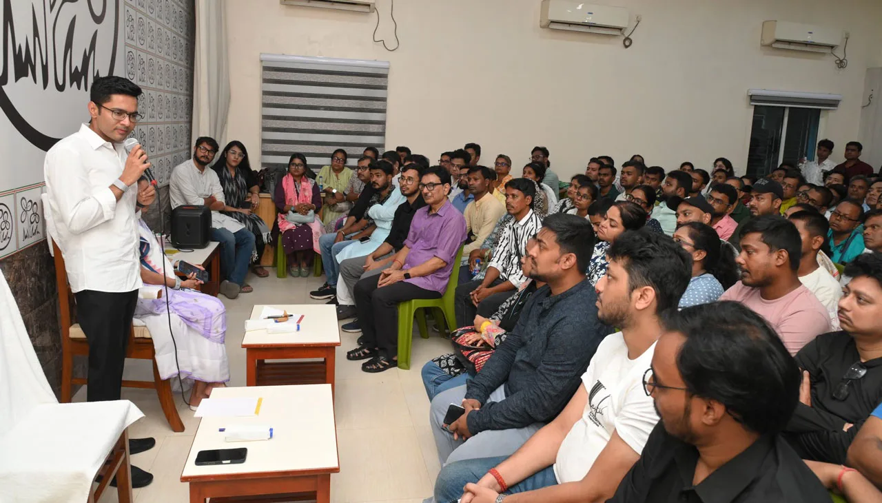 Speaker in a white shirt delivers a talk with a microphone to a large audience seated in a seminar room.