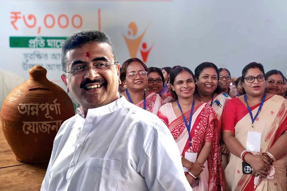 Smiling man in a white shirt at the front of a group of women in sarees during a ceremony, with a large clay pot in the background.
